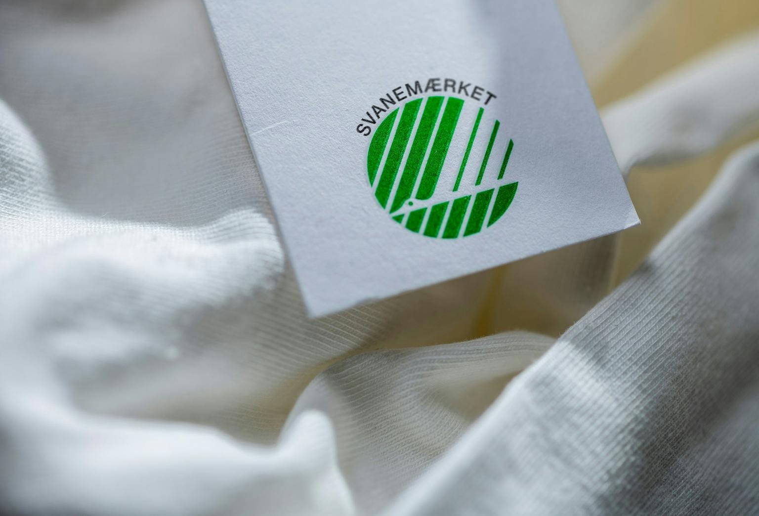 Close uf hvid bluse og hangtag med Svanemærkets logo